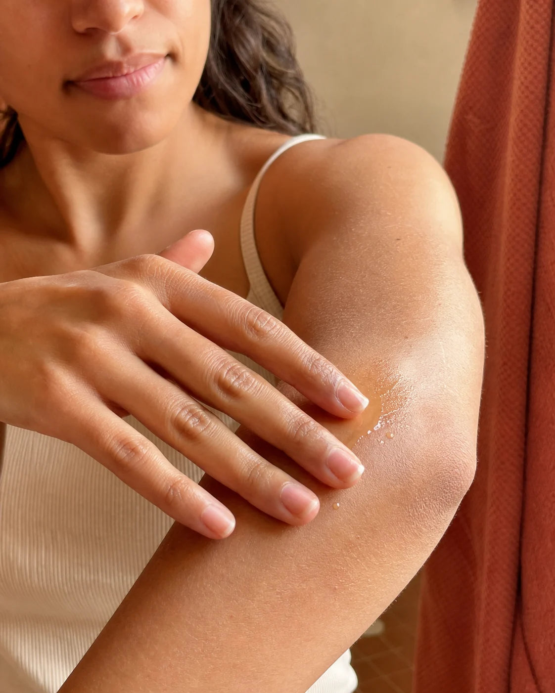 Woman smoothing botanical oil over dry-feeling skin on her elbow